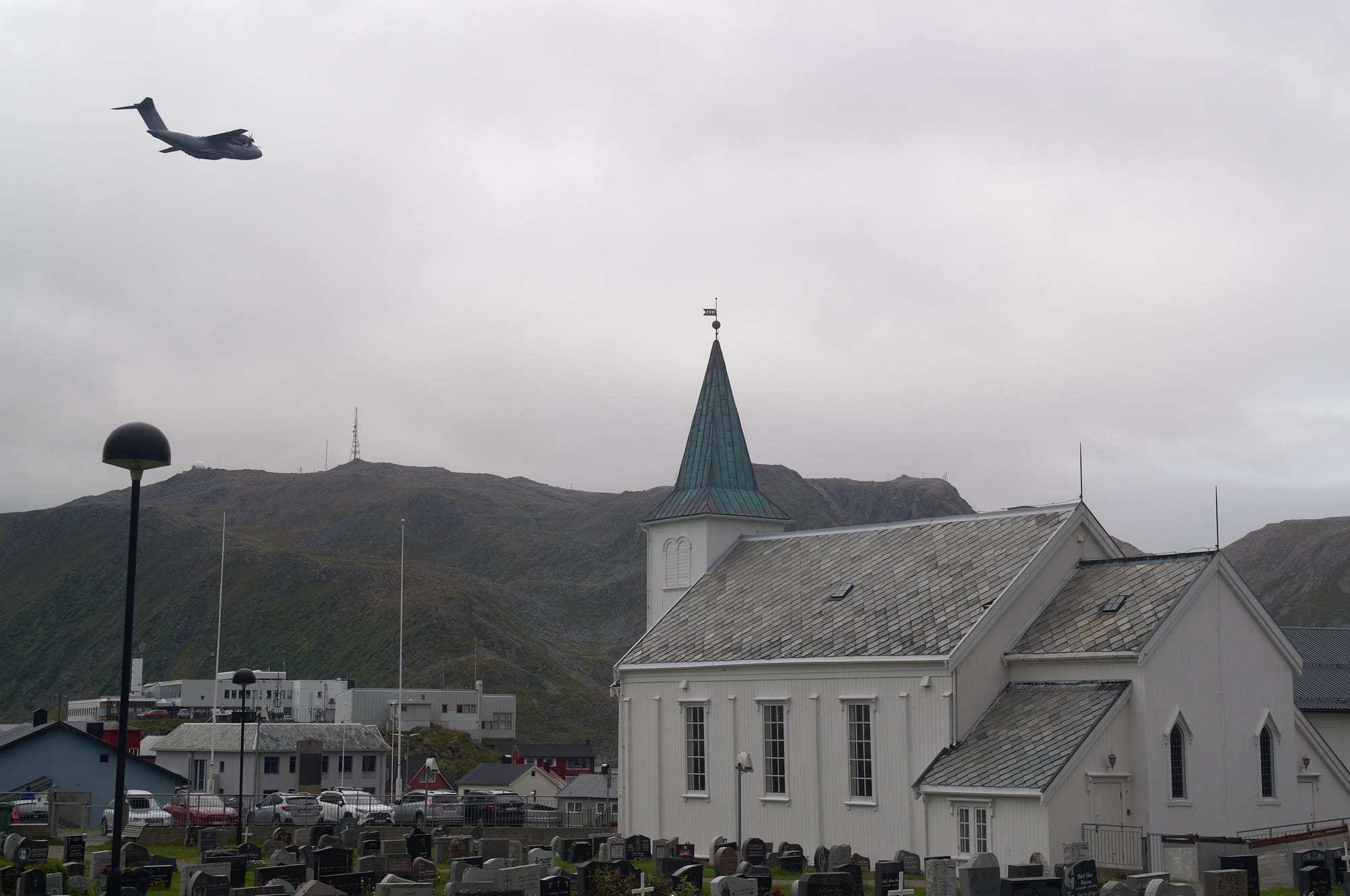 White church with large Norwegian air force transport flying overhead.