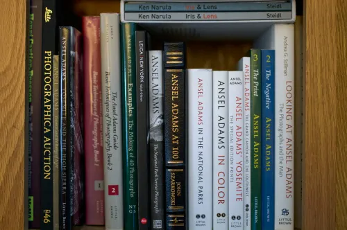A shelf of books mostly including works by Ansel Adams