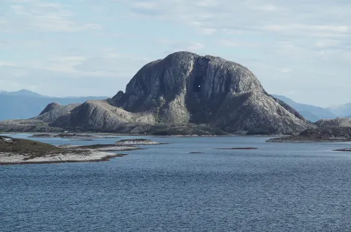 Large rock formation in the ocean with hole worn in the center.