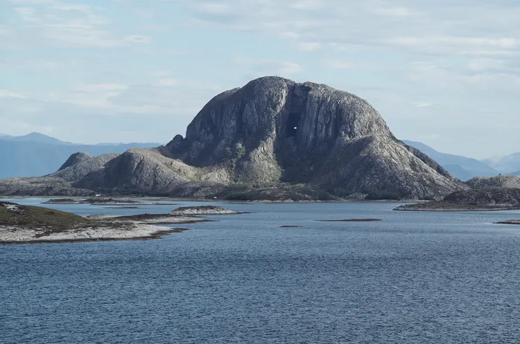 Large rock formation in the ocean with hole worn in the center.