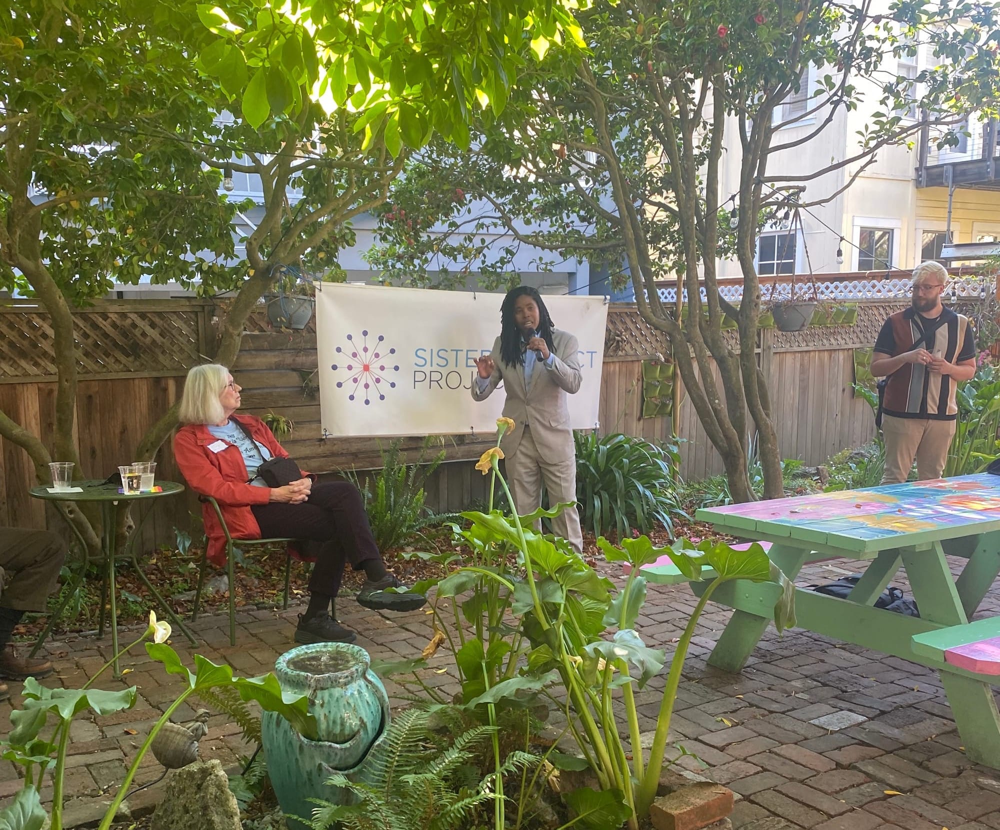 Dallas Harris, Nevada State Senate candidate speaking at San Francisco fundraiser in a backyard with plants 