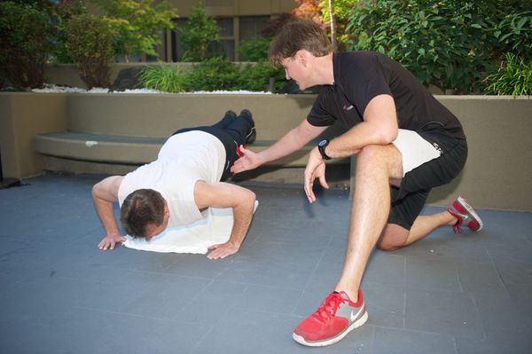 Man over 40 doing push-up with correct form during personal training session in Downtown Vancouver.