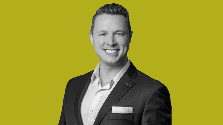 Kirk Sigmon wearing a suit and smiling at the camera.