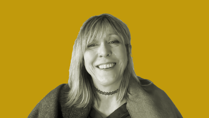 Mary Flanagan in a shawl and black necklace smiles in front of an orange background.