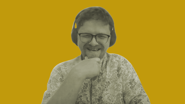 Benjamin Horn smiles at the camera wearing glasses and headphones in a flowery shirt.