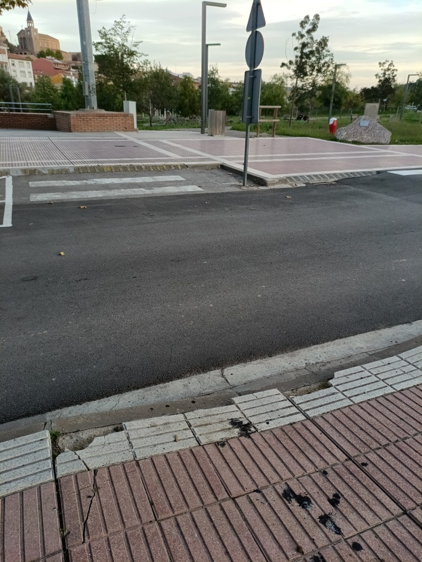 Paso de peatones con las bandas casi borradas, con la acera y el pavimento podotáctil conduciendo hasta él