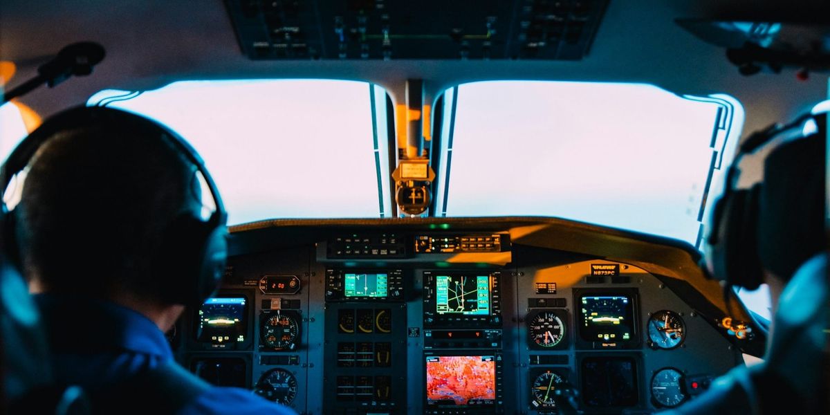 Two pilots watch on in airline cockpit while the autopilot flies.