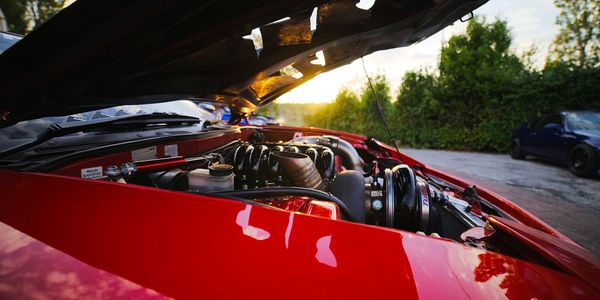 A car with its hood up, exposing the engine underneath, the working parts normally hidden beneath a smooth exterior.
