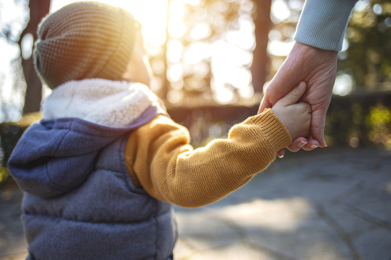 A young boy holding their parent's hand