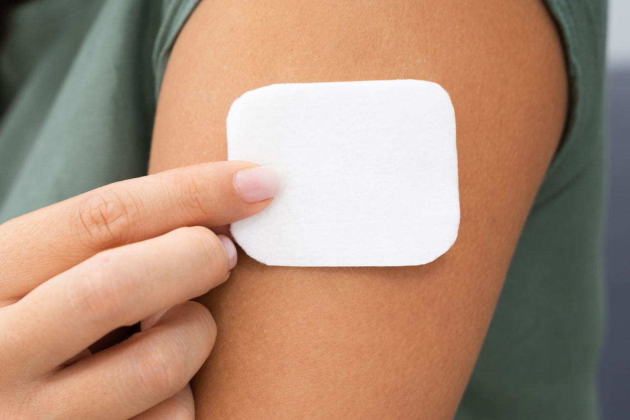 A woman applying a patch to their arm