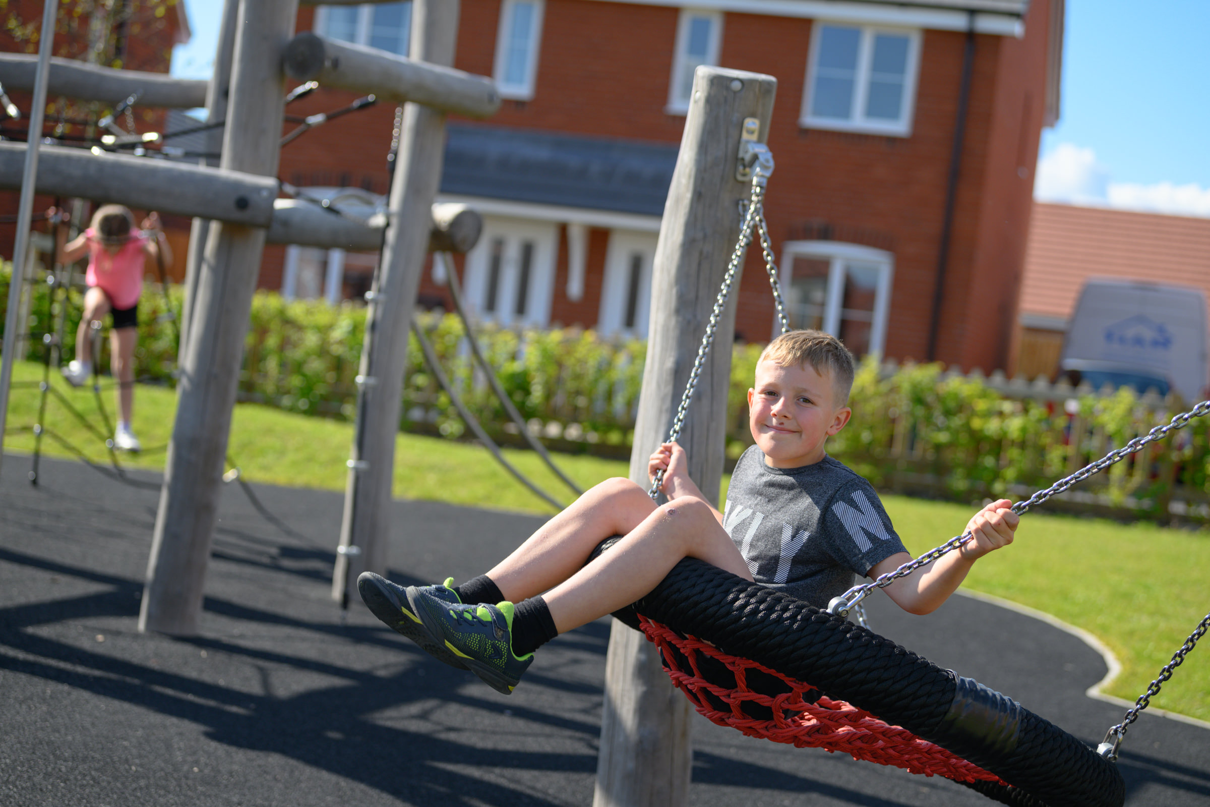A boy swinging on a swing at a park outside a new housing development