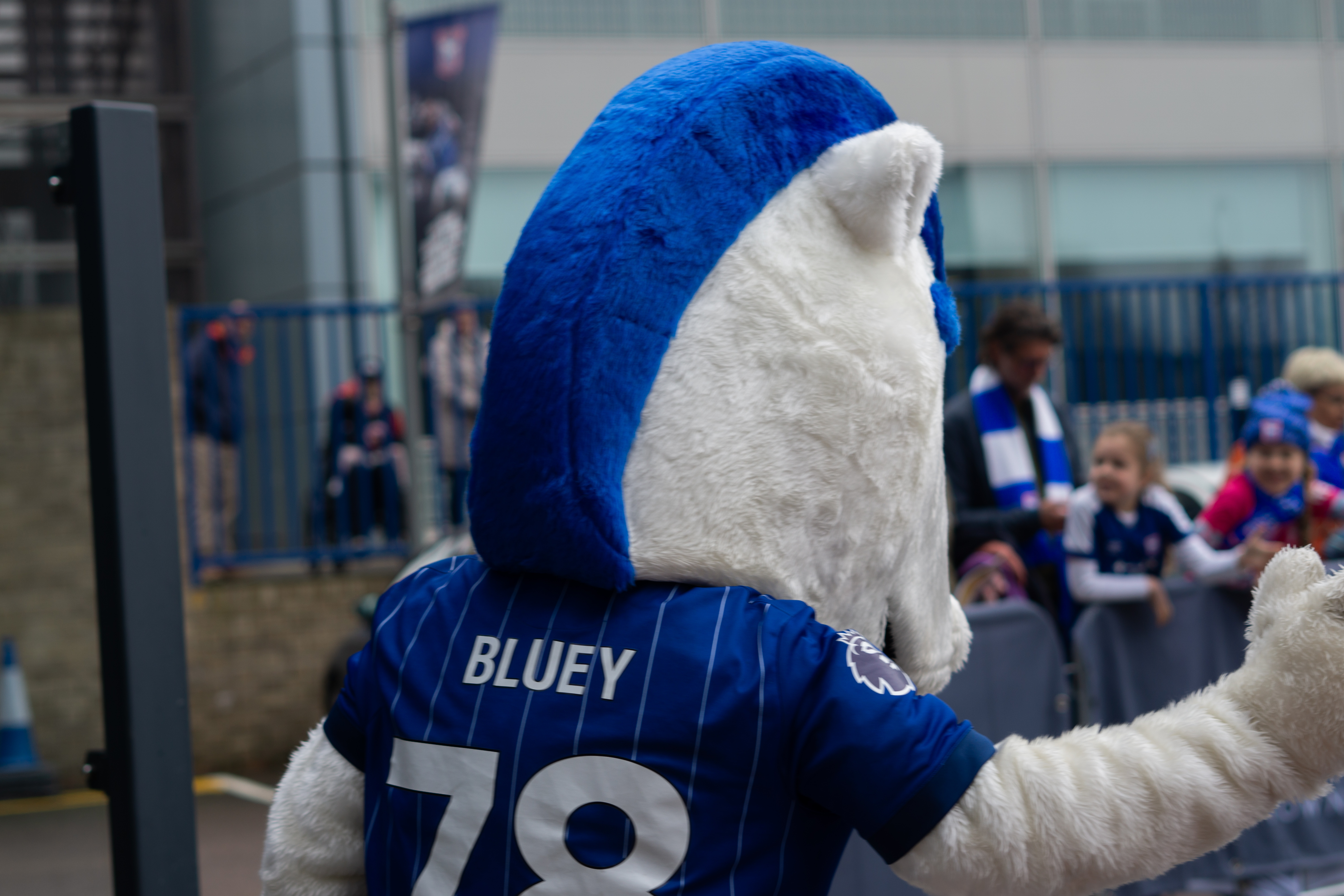 Club mascot bluey waving at waiting fans