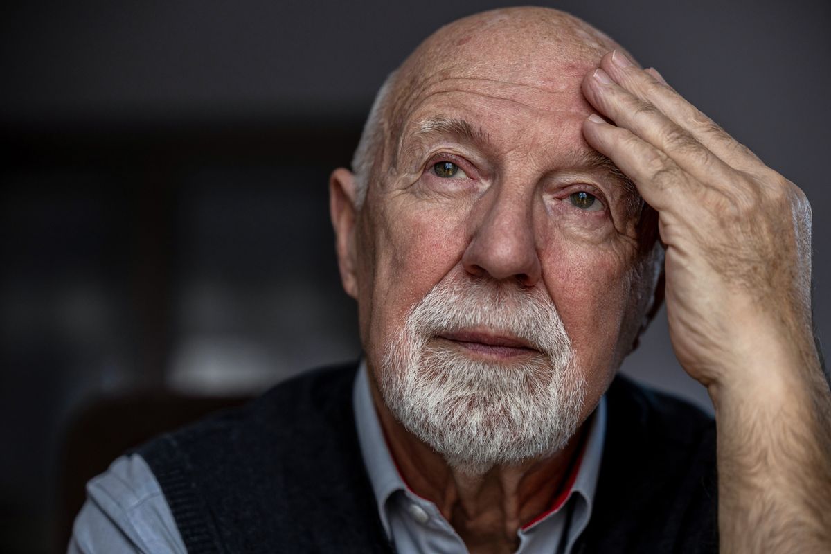 An elderly man with his hand on his head