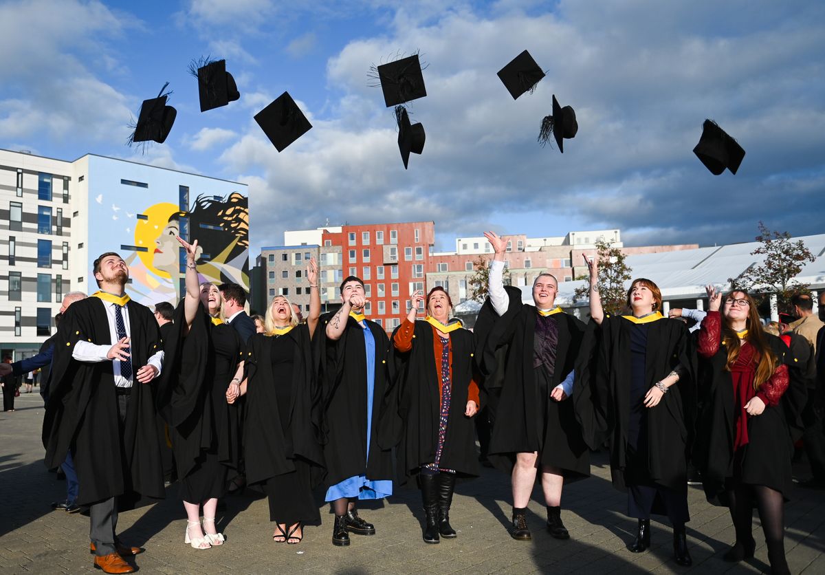 young people throwing hats in air