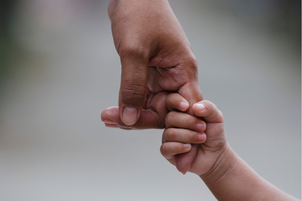 Photo of a child's hand gripping onto an adult's finger