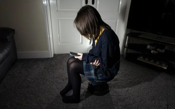 An anxious child on her phone at home