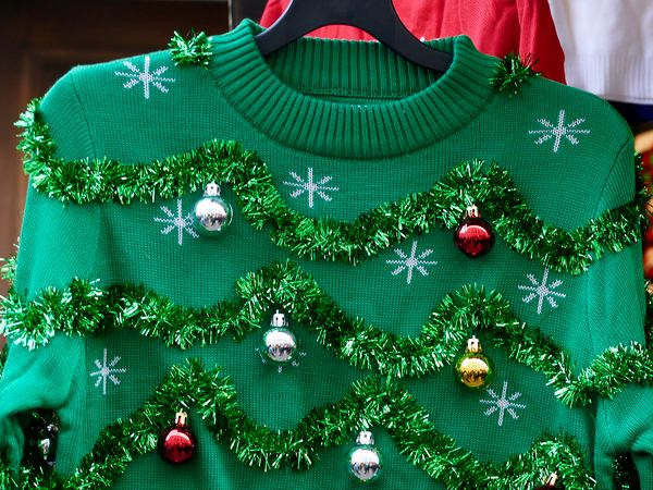 A green Christmas jumper with tinsel and baubles on it
