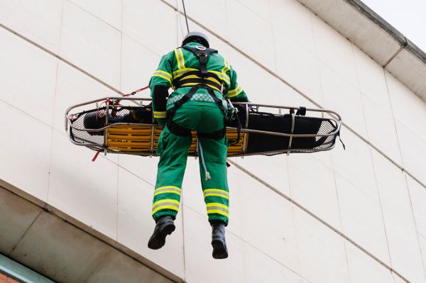A man being lowered from a building on a stretcher