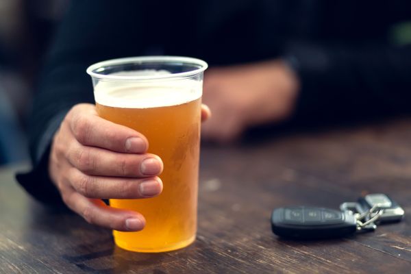 A man drinking a beer next to his car keys
