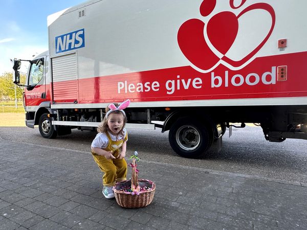 Etta giving out Easter eggs at the hospital in front of a Please Give Blood truck