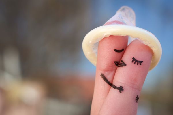 A condom on two fingers with eyes and arms drawn on them so they look like they're kissing