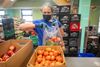 A worker fills a plastic bag with produce.