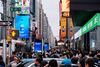 A huge crowd of people mill around a chaotic Times Square.