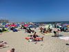 Hundreds of beachgoers sit on blankets on a brilliant summer day in the Rockaways.