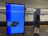 An MTA information screen has been punched out and displays glitches on the subway platform.