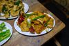 A plate of beef tripe with dried red chilis from Zhego, on a wooden table surrounded by other dishes.
