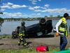 An SUV sits upside down in the bike path in Riverside Park, FDNY and EMS workers walk by.