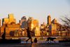 A woman walks her dogs along South Street with a view towards the Brooklyn waterfront.