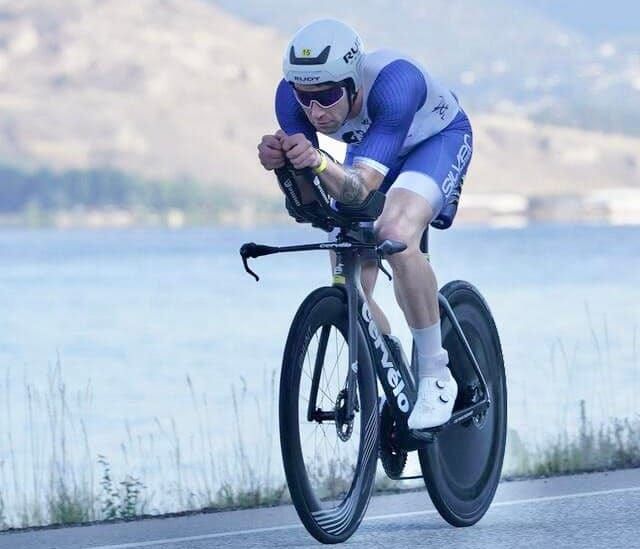Eric Lauricella in aero position on a time-trial bike on a lakeside road