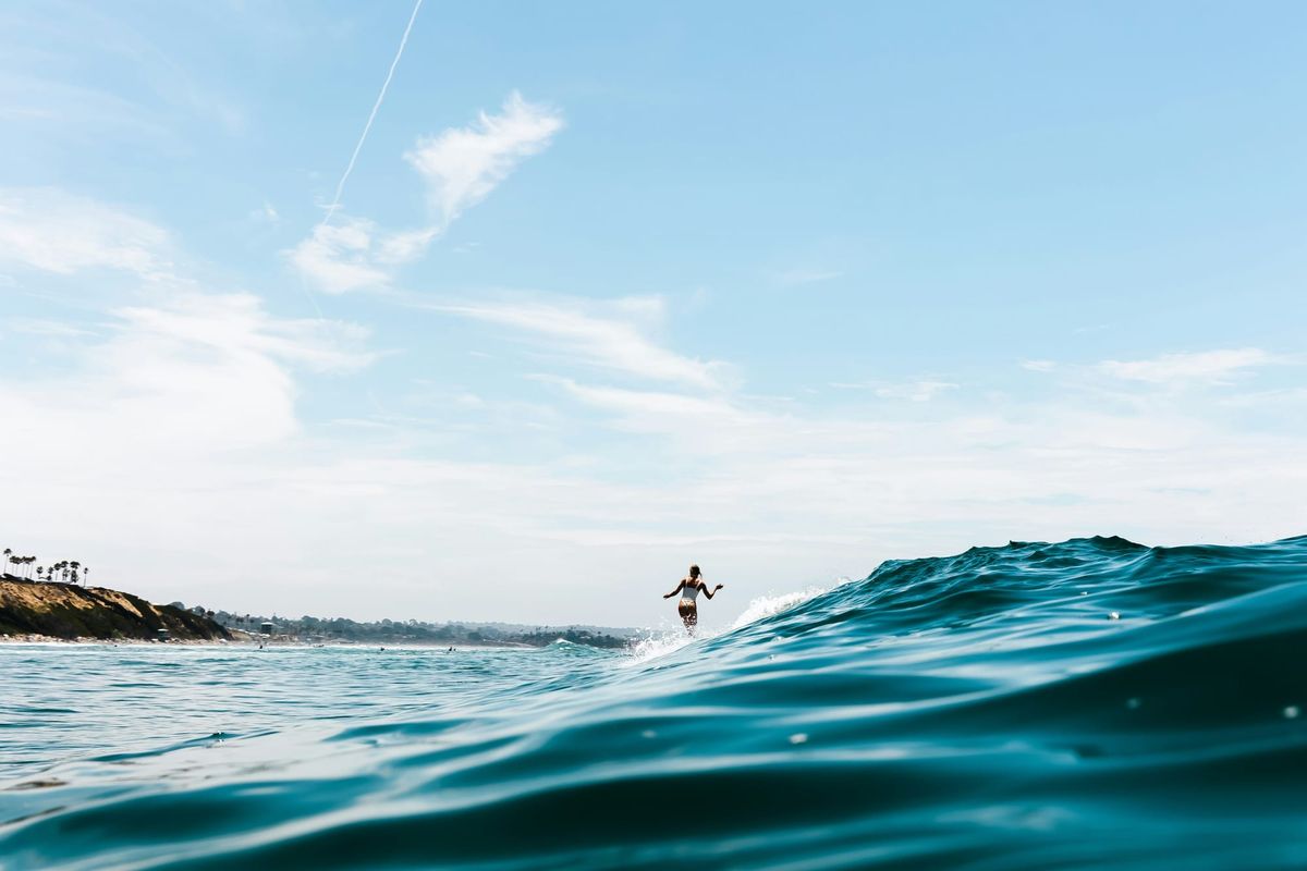 A wide shot of the ocean with a small surfer on a wave in the distance.
