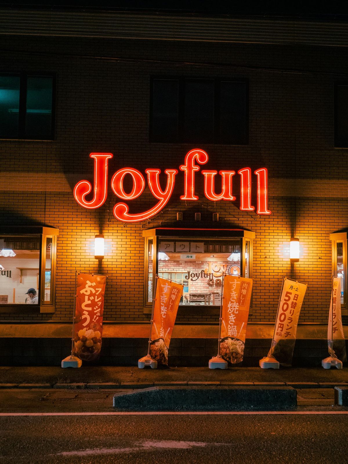 夜晚霓虹燈招牌「Joyful」在磚牆建築上，象徵即使在困難時刻也能選擇快樂與正向情緒