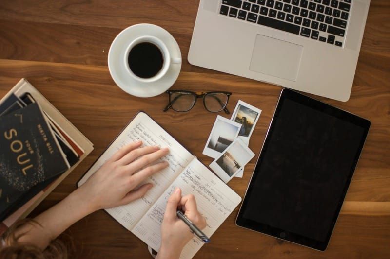 Overhead view of workspace with notebook and coffee representing consistent work without applause