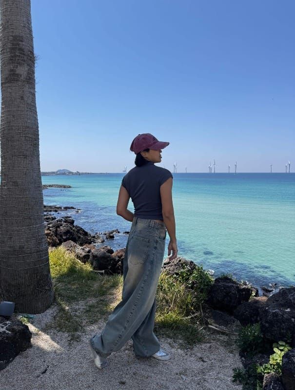 女人獨自站在濟州島海邊凝視大海，情緒療癒與正向思考的自我覺察時刻