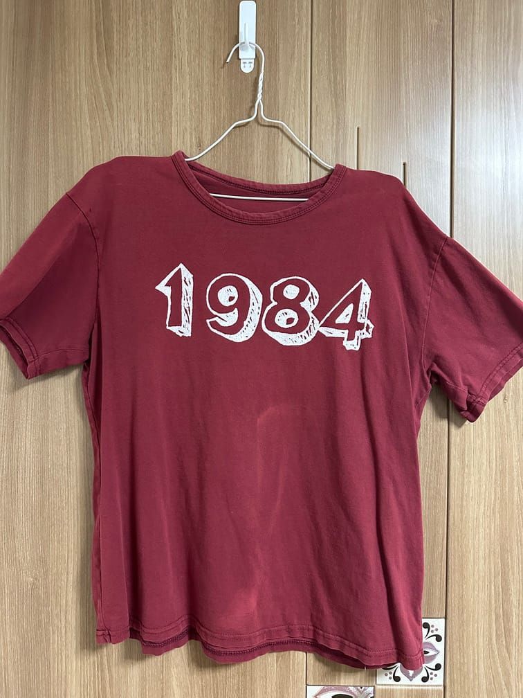 붉은 티셔츠의 앞면에 흰 글씨로 1984라고 적혀 있다. 글꼴은 마커로 입체 효과를 준 듯한 글꼴이다.