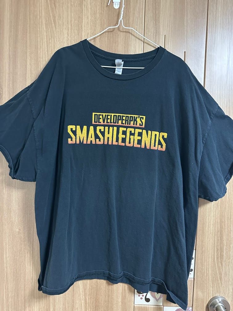 검은 티셔츠의 가슴에 노란 색으로 "DEVELOPERPK'S SMASHLEGENDS"라고 적혀 있다.