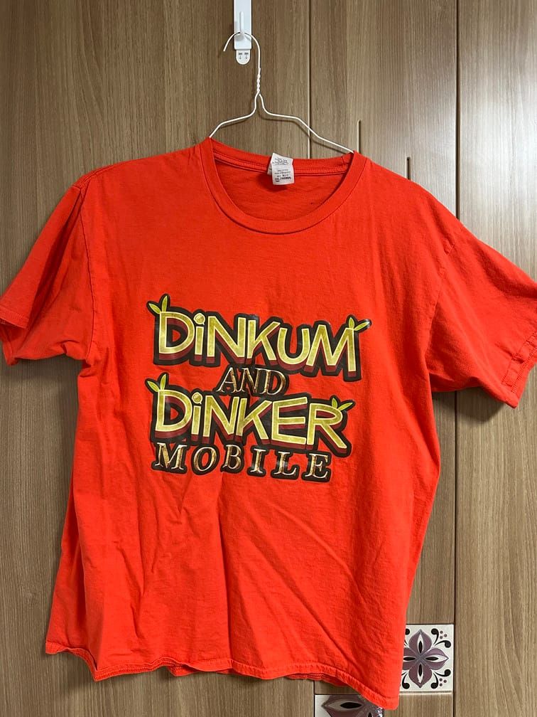주황색 티셔츠의 가운데에 "DINKUM AND DINKER MOBILE"이라는 로고가 있다.