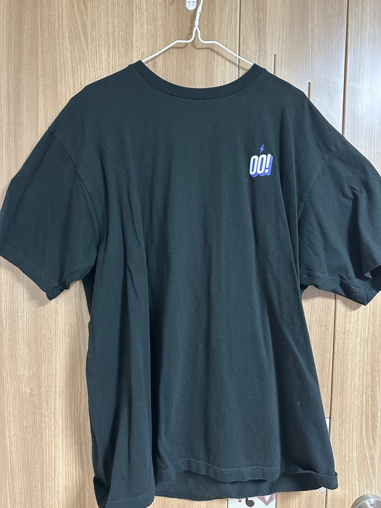 검은 반팔 티셔츠의 왼쪽 가슴 부분에 OO! 라는 흰 글자와 번개 마크가 그려져 있다.