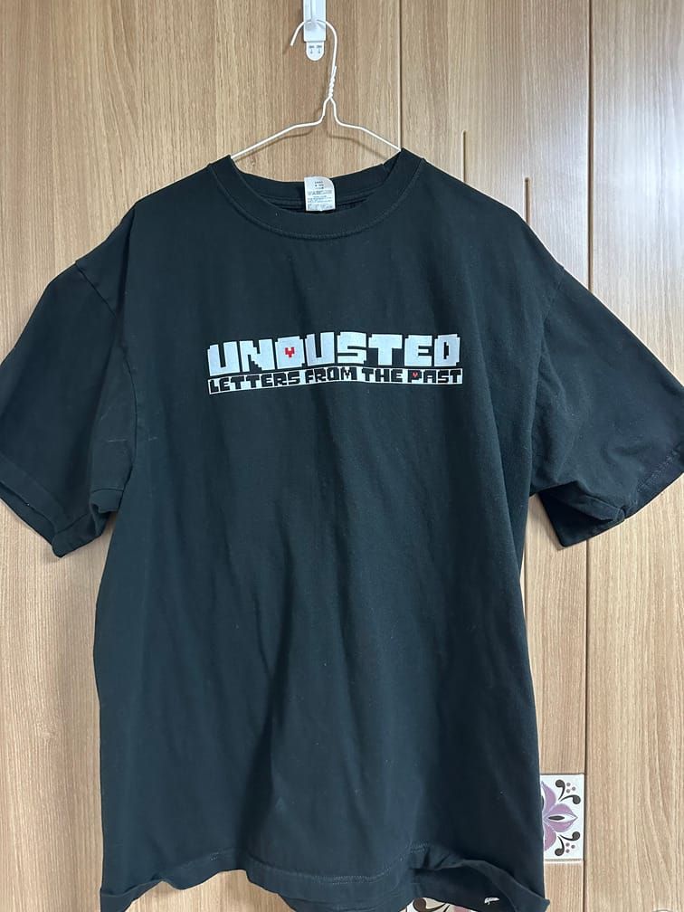 검은 티셔츠의 가슴 부분에 『Undusted: Letters from the Past』라는 로고가 박힌 티셔츠의 사진.