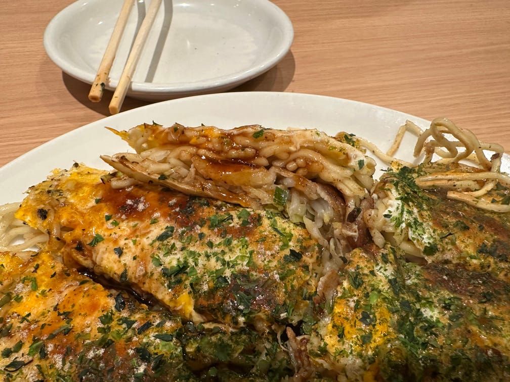 접시에 차려진 오코노미야끼의 단면을 근접하게 찍은 사진. 야끼소바의 면이 보인다.