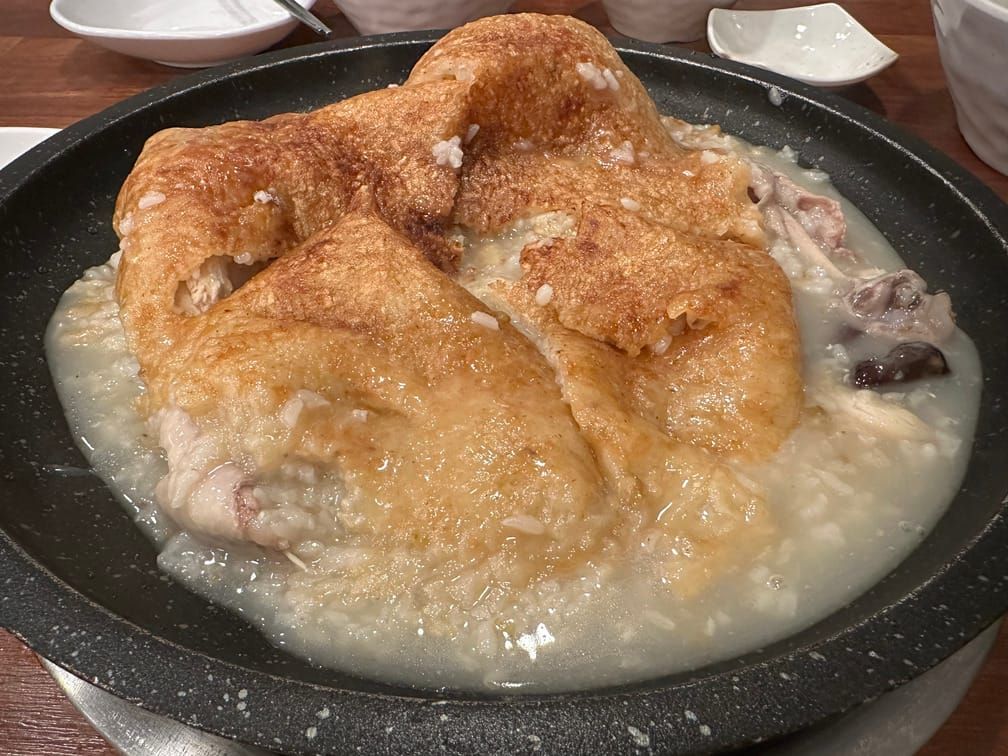 넓은 돌솥 안에 닭죽 같은 요리가 담겨 있는데, 돌솥크기만한 누룽지로 덮여있다.