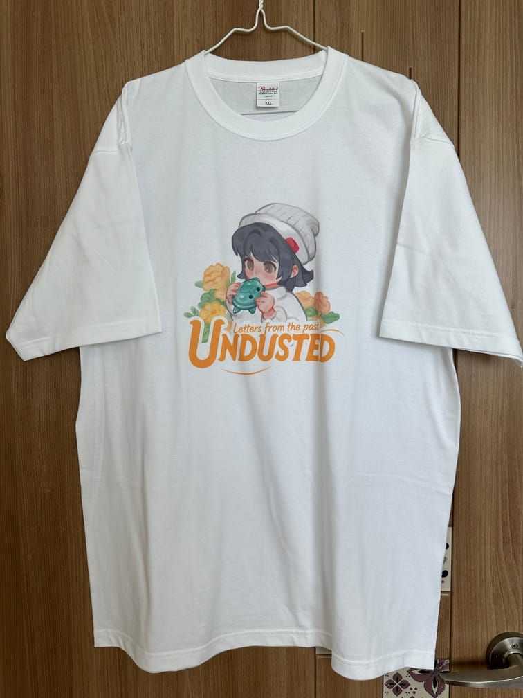 흰 티셔츠에 Undusted(Letters from the past)라는 글자와, 거북이 모양 오카리나를 부는 소녀를 묘사한 그림이 그려져 있다.