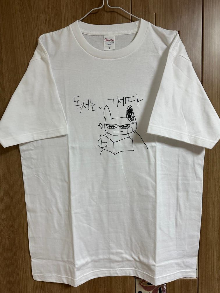 흰 티셔츠의 가슴팍에 그림판의 볼펜 기능으로 대충 그린 것 같은, 선글라스를 끼고 책을 읽는 동물 캐릭터와 함께 '독서는… 기세다'라고 적힌 그림.