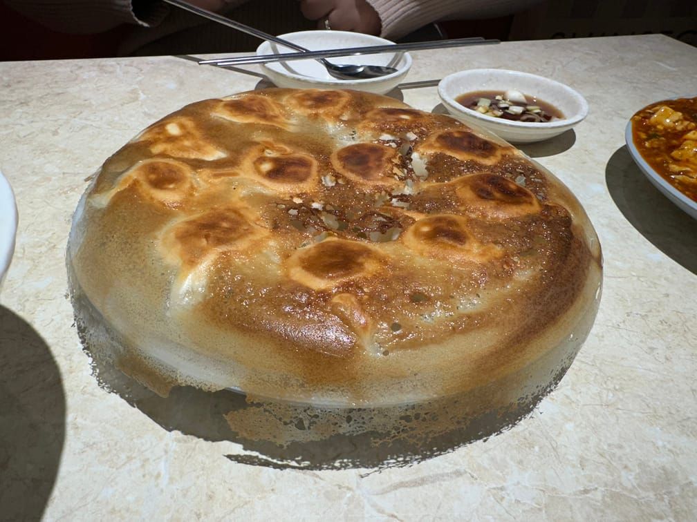 테이븟의 그릇 위에 냄비에서 떼어낸 듯 동그랗게 구워진 모양의 무언가가 차려져 있다.