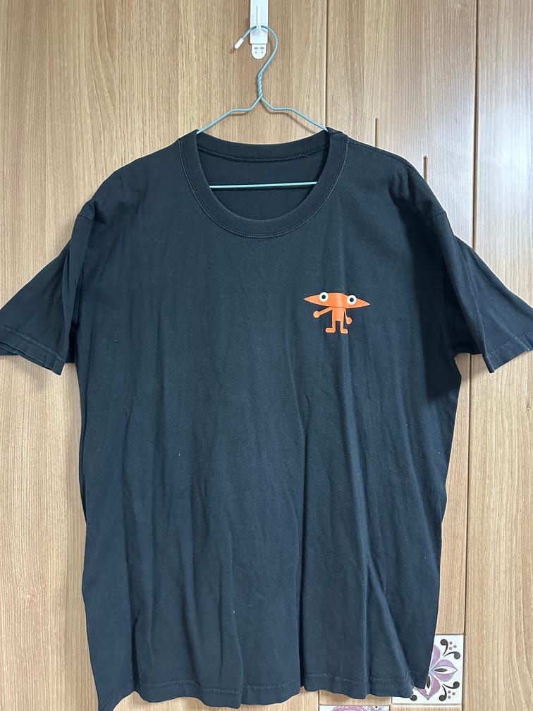 검은 반팔 티셔츠의 왼쪽 가슴 부분에, 대학 KAIST의 마스코트 『넙죽이』의 주황색 버전이 그려져 있다.