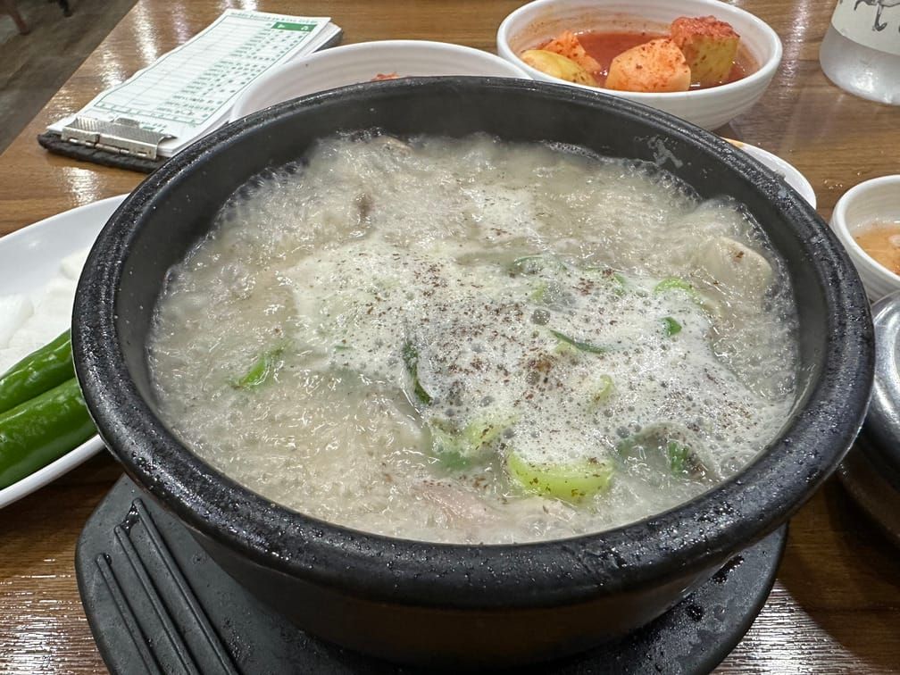 보글보글 끓고 있는 뽀얀 국물에 채썬 파와 들깨가루가 보이는 뚝배기.