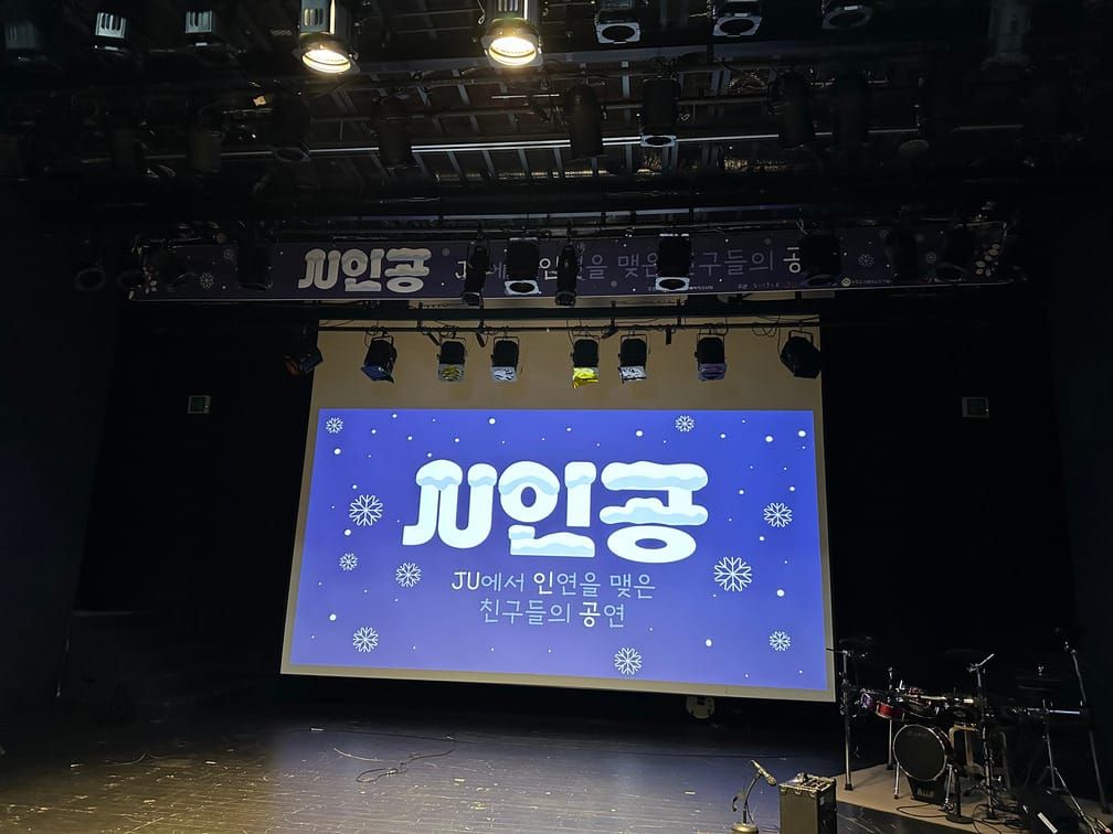 무대의 모습. 『JU인공』이라는 제목과 함께, "JU에서 인연을 맺은 친구들의 공연"이라는 문구가 그려진 눈꽃 테마의 슬라이드가 띄워져 있다.